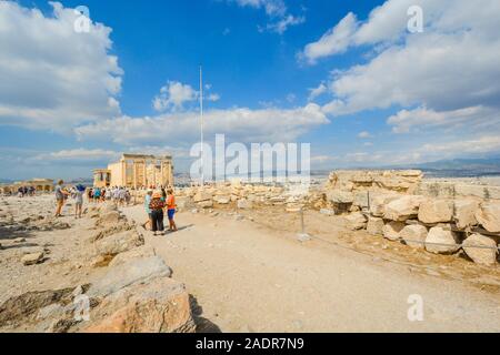 Tourists enjoying a hot day on Acropolis Hill in Athens Greece in front of the ancient Erechtheum with the Parthenon in view behind. Stock Photo