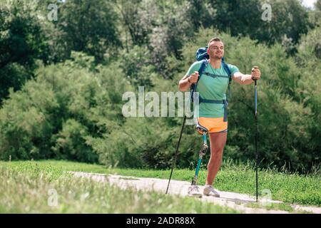 Delighted handicap man enjoying Nordic walking outdoors Stock Photo