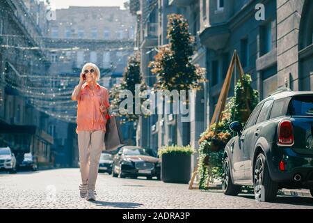 Elderly lady walking and talking on the phone Stock Photo
