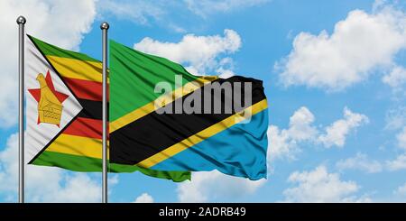 Tanzania and Zimbabwe flag waving in the wind against white cloudy blue ...
