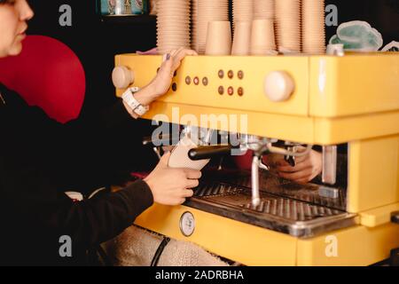 Female barista preparing tea using coffee machine Stock Photo