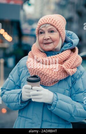 Aged woman standing alone in winter day and looking away Stock Photo