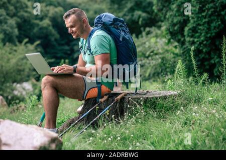 Cheerful man with prosthesis using his laptop outdoors Stock Photo