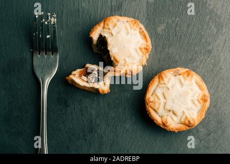 Metal fork lying near two mince pies on black surface Stock Photo