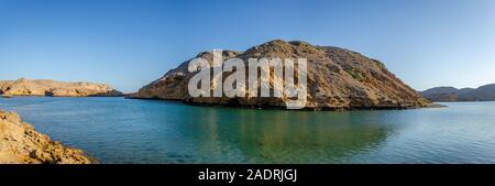 Clear turquoise water, barren hills and clear sky. Oman virgin seascape for you. Stock Photo