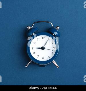 Classic alarm clock on blue background. Minimal styled photo. Stock Photo