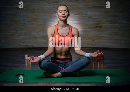 Beautiful sporty lady smiling while meditating with closed eyes Stock Photo