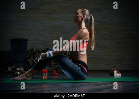 Long haired young lady sitting with straight back on the yoga mat Stock Photo