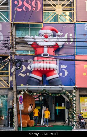 A large Santa Claus figure attached above the entrance of a small shopping plaza in Wang Burapha area, Bangkok, Thailand Stock Photo