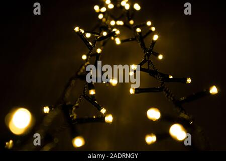 Blurred Christmas led lights garland with selected focus on dark background. Stock Photo