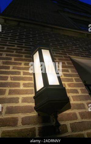 Lantern mounted on the outside wall of a tall brick building, on Manhattan's Upper East Side at night, New York City Stock Photo