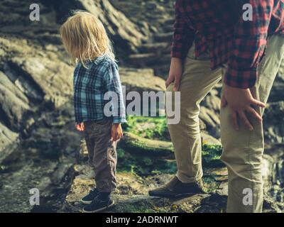 A father and his little toddler are walking on rocky coastal ground Stock Photo