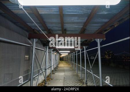 Walkway underneath a scaffolding on Manhattan's Upper East Side, at night, New York City Stock Photo