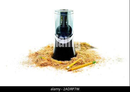 An electric pencil sharpener surrounded by pencil shavings and a few pencils lying at the bottom, isolated on white background Stock Photo