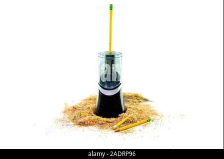 An electric pencil sharpener surrounded by pencil shavings, a pencil sticking out from the top, and a few pencils lying at the bottom, isolated on whi Stock Photo