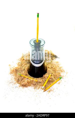 An electric pencil sharpener surrounded by pencil shavings, a pencil sticking out from the top, and a few pencils lying at the bottom, isolated on whi Stock Photo