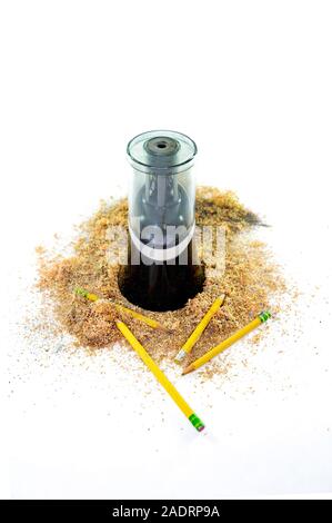 An electric pencil sharpener surrounded by pencil shavings and a few pencils lying at the bottom, isolated on white background Stock Photo