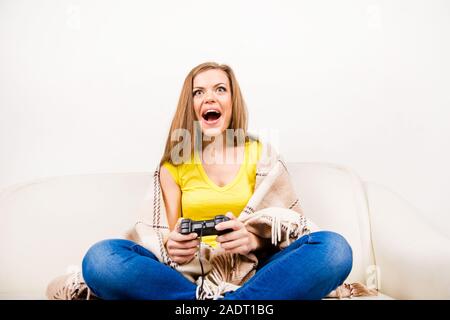 Excited girl playing with game console on sofa Stock Photo