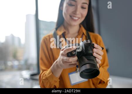 Dark-haired young cute reporter checking photos in camera Stock Photo