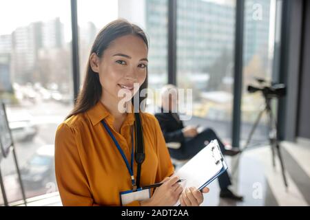 Dark-haired young cute reporter looking happy and smiling Stock Photo