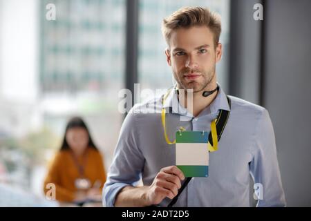 Young man in a blue shirt showing his badge Stock Photo