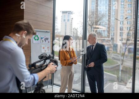 Young asian reporter having a conversation with a grey-haired man Stock Photo