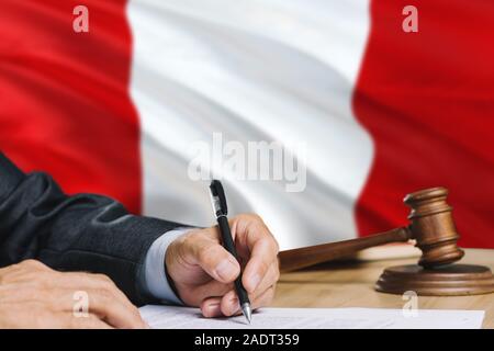 Judge writing on paper in courtroom with Peru flag background. Wooden gavel of equality theme and legal concept. Stock Photo
