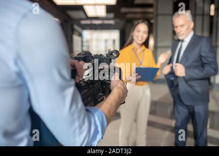 Asian female reporter in beige pants smiling nicely Stock Photo