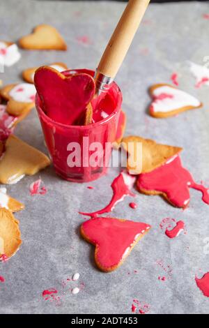 glass full of red cream to paint biscuits with brush and fallen biscui Stock Photo
