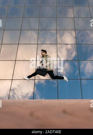 Businessman is jumping with a glazed building in the back Stock Photo