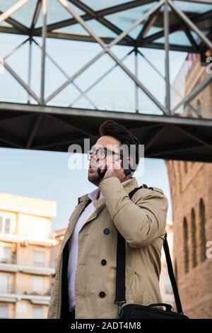 Businessman with a coat is calling with his smartphone Stock Photo