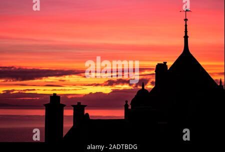 Lyme Regis, Dorset, UK. 5th December 2019. UK Weather:  Beautiful winter sunrise at Lyme Regis. Buildings and trees are silhouetted against gorgeous colours in the sky on a chilly morning. Credit: Celia McMahon/Alamy Live News. Stock Photo