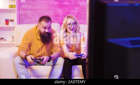 Upset young couple after losing while playing online video games using wireless controllers. Disappointment on their faces Stock Photo