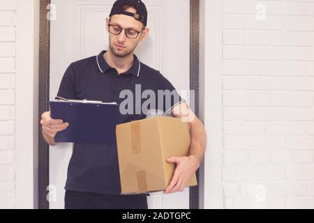 Portrait of a courier with a box of parcel and documents for signature. Stock Photo