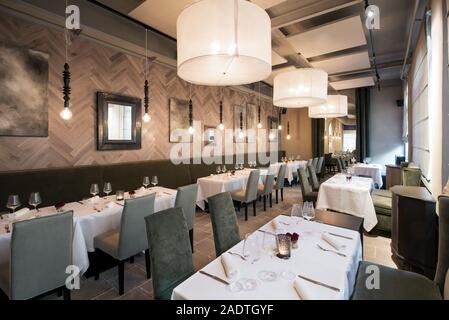 Interior of a modern upmarket restaurant with empty tables set with cloths, cutlery and glassware in a receding view Stock Photo