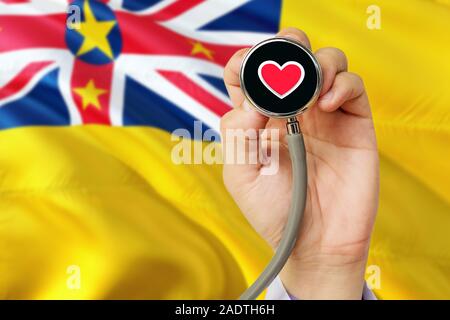 Doctor holding stethoscope with red love heart. National Niue flag background. Healthcare system concept, medical theme. Stock Photo