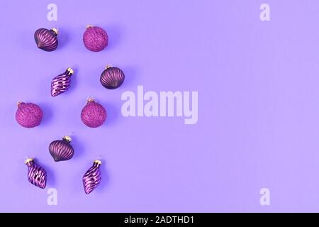Seasonal Christmas flat lay with gittering tree baubles on left side and empty purple copy space on right side on light purple background Stock Photo
