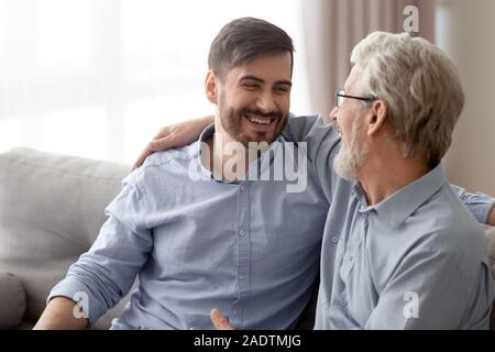 Aged father grownup son laughing having fun sitting on couch Stock Photo