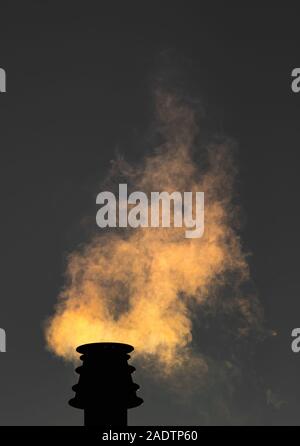 Smoke rising from a small chimney at night. Stock Photo