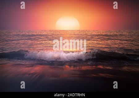 red sunset on beach with a wave on the shore and big sun Stock Photo