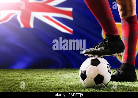 Close up legs of Turks And Caicos Islands football team player in red socks, shoes on soccer ball at the free kick or penalty spot playing on grass. Stock Photo