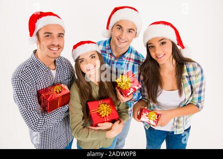 Happy young people in santa hats holding christmas presents Stock Photo