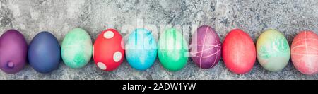 Panorama, colorful dyed easter eggs in a line on grey background, easter season handicraft Stock Photo