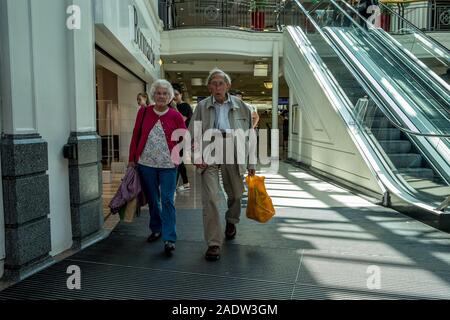 An elderly couple doing their shopping in a town centre shopping mall. Stock Photo