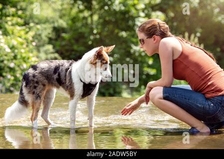 Outdoor walk with the dog, Woman and Whelp on a flat river at the summer time Stock Photo