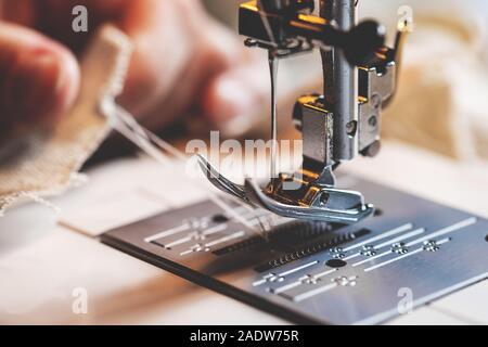 hand is holding the lower thread behind the presser foot of a sewing machine Stock Photo