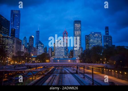 City skyline of illuminated skyscrapers in downtown Chicago Loop area and railway lines and people waiting for train, Chicago, Illinois, USA Stock Photo