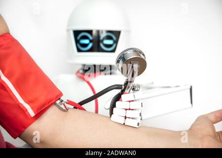 medical assistance robot is checking the blood pressure of a male patient, while using a stethoscope Stock Photo
