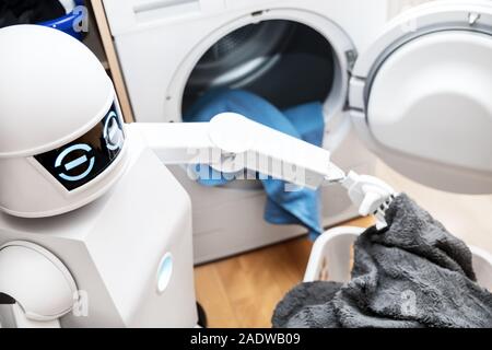 ambient assisted living robot or cyborg is working in the household. robot is putting some clothes in the dryer Stock Photo