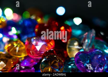Multi-colored glass pebbles glow in the dark with bright saturated colors. Close-up. Multi-colored faceted glass stones Stock Photo